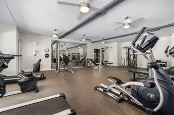 Fitness center with ceiling fans and various exercise equipment.